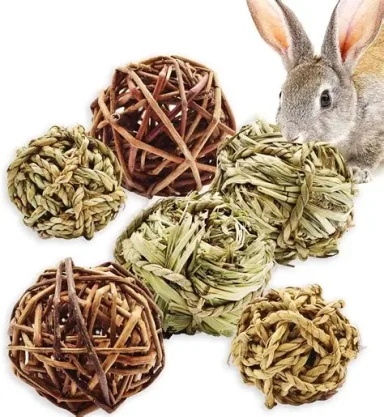 A rabbit near natural chew toys made of twigs and grasses.